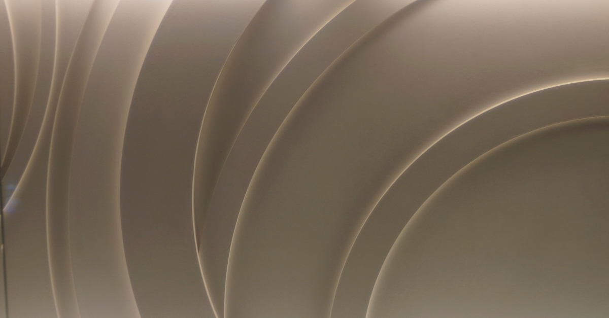 Curved metallic panels create an abstract, layered pattern with a smooth gradient, forming a visually engaging texture.