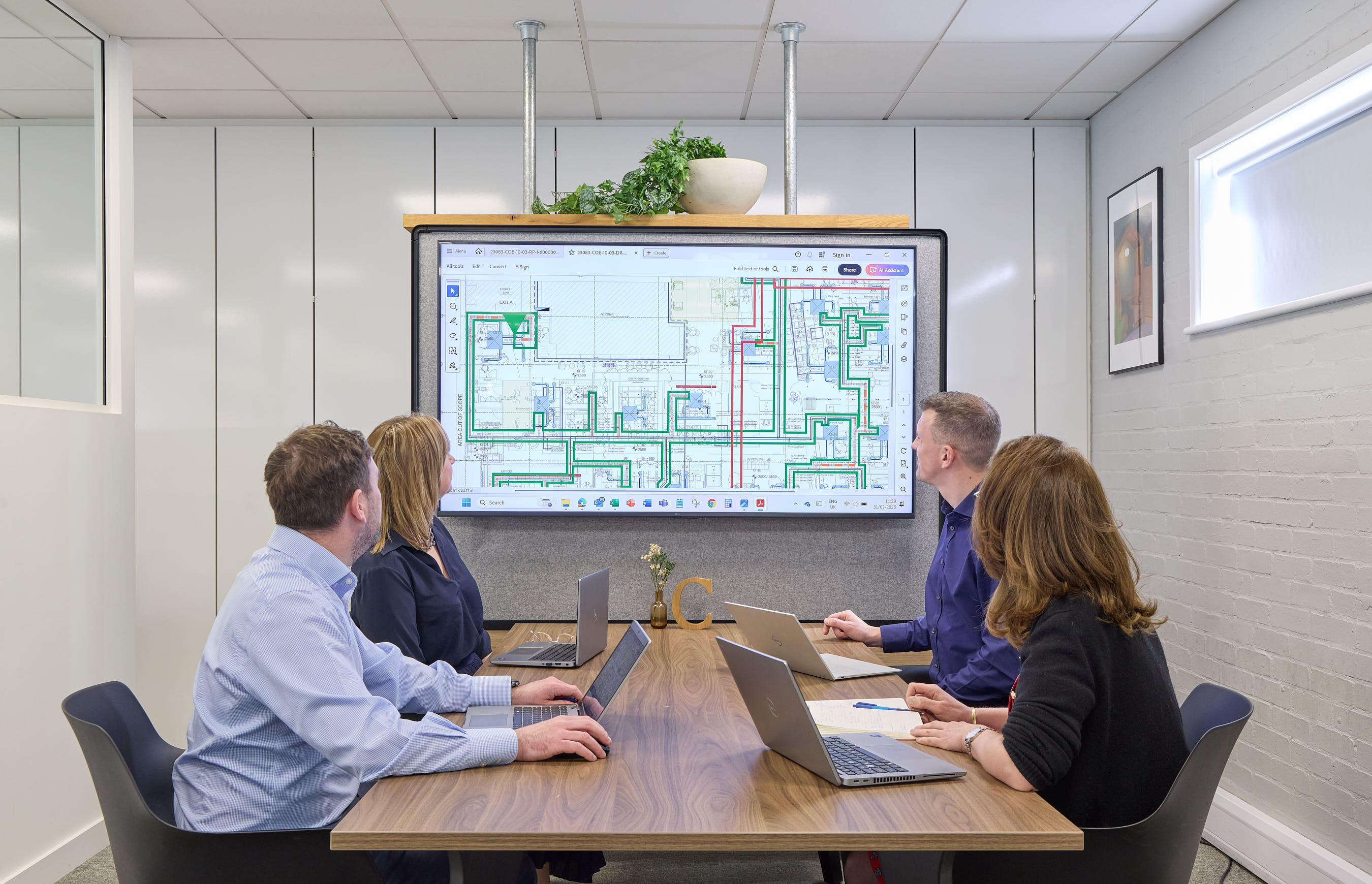 brightly lit, modern office with rows of empty desks, ergonomic chairs, and large windows