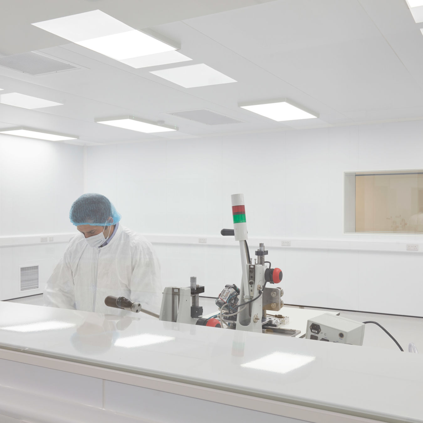 Laboratory technician working in a cleanroom environment with sterile white surfaces and equipment, part of a COEL Lab Planning project for Sense Bio.