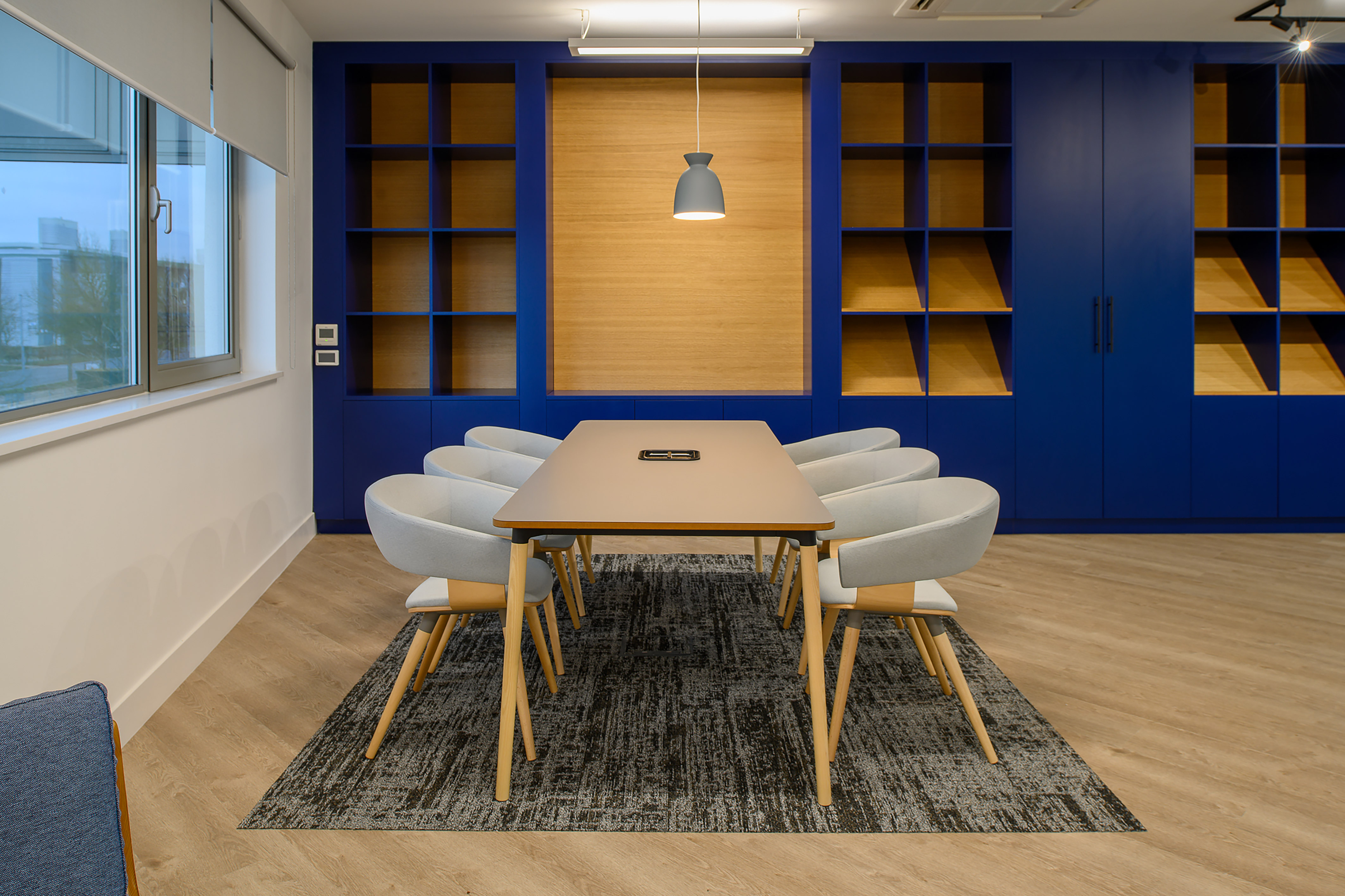 modern office meeting room with a long table, six chairs, and blue built-in shelves