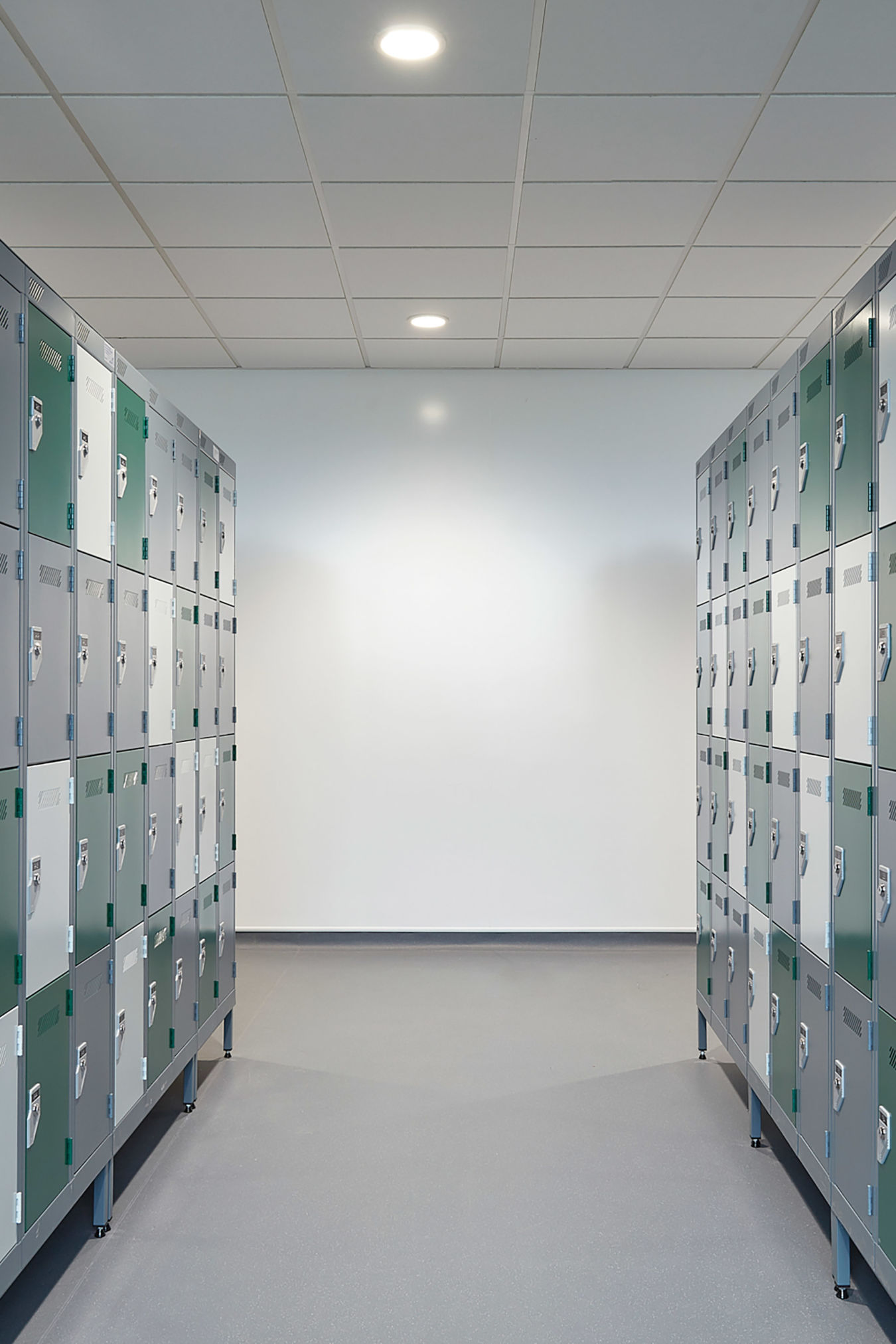 hallway lined with green and gray lockers on both sides, brightly lit with overhead lights, creating a clean and orderly atmosphere