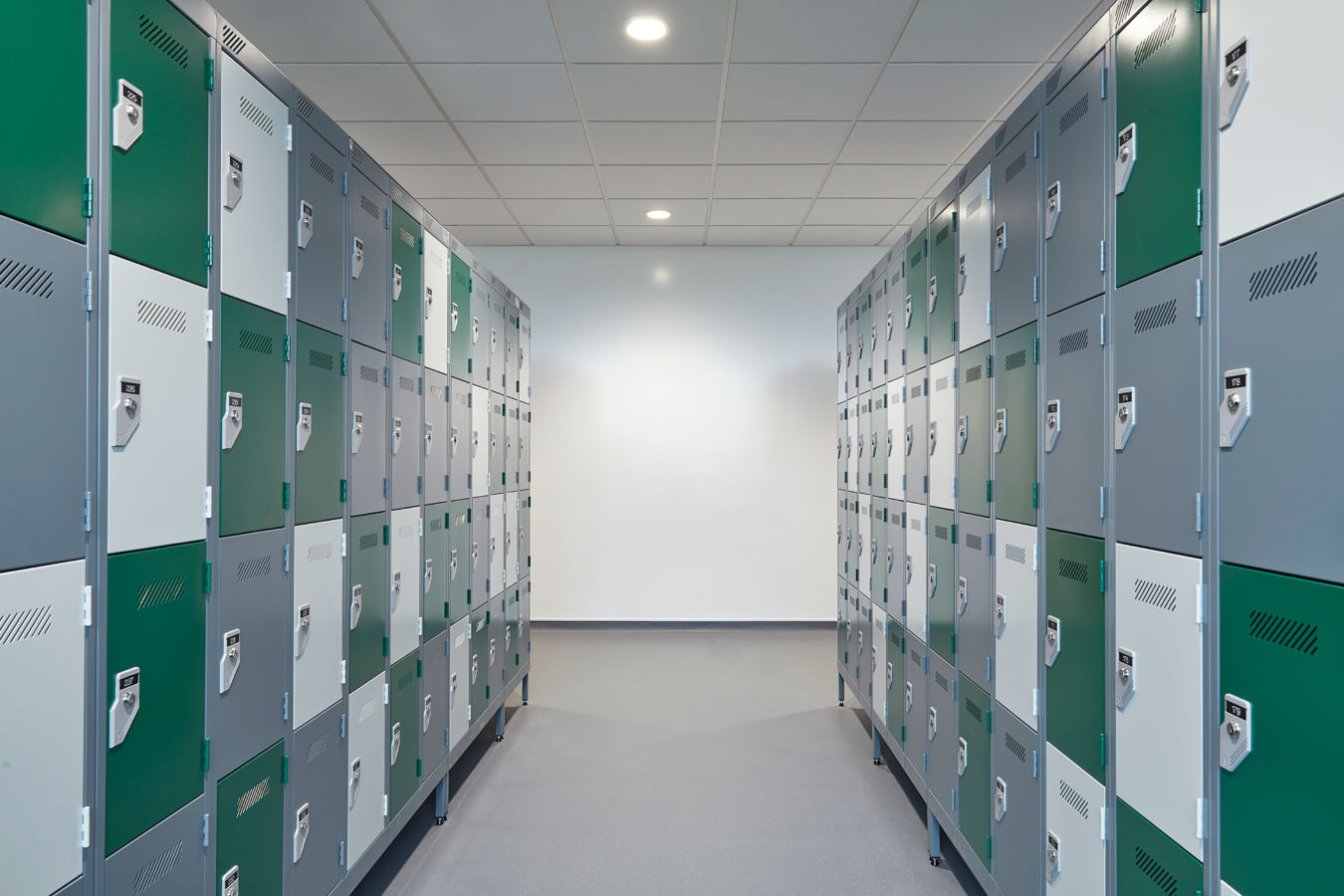 hallway lined with green and gray lockers on both sides, brightly lit with overhead lights, creating a clean and orderly atmosphere